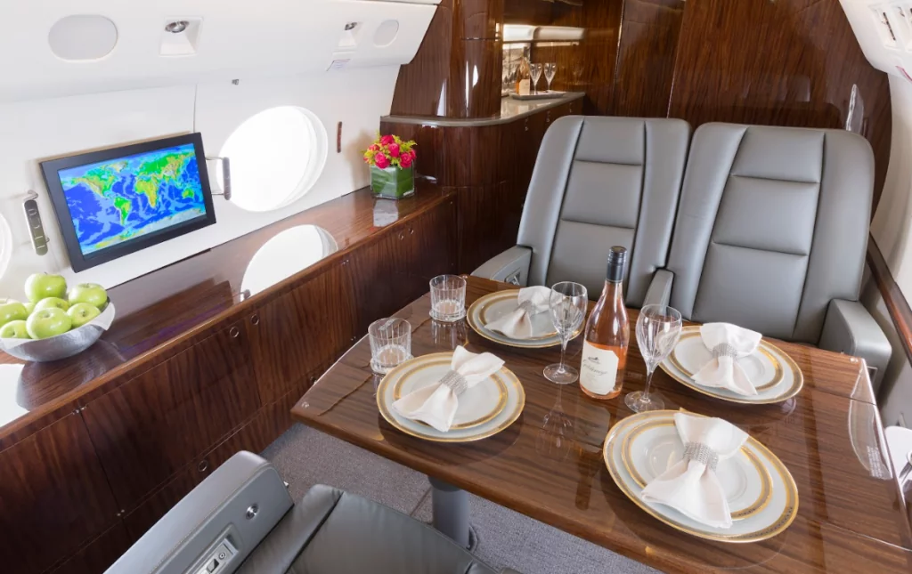 private luxury jets interior with deep wood paneling, leather seats, flowers, and fine dinnerware