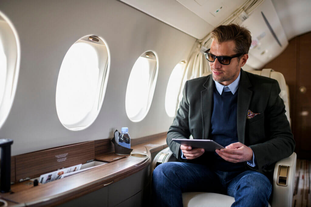 man wearing sunglasses looking out window and enjoying the advantages of flying private